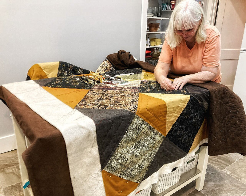 Anne Watcher of Crafted Comforts at her work table making a handmade quilt!